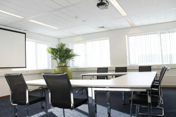 Vergaderruimte aan de Laan van s-Gravenmade met moderne inrichting, grote ramen en een projector.